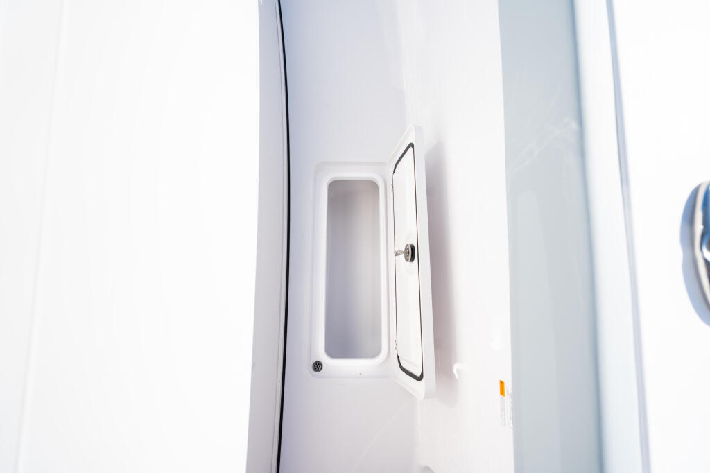 Open cabin door with rectangular window on white boat exterior
