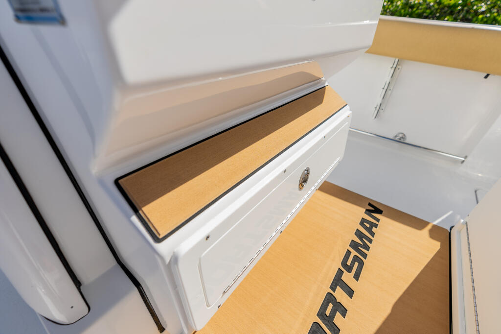 Cushioned footrest with storage compartment on boat console, featuring tan padding and white trim