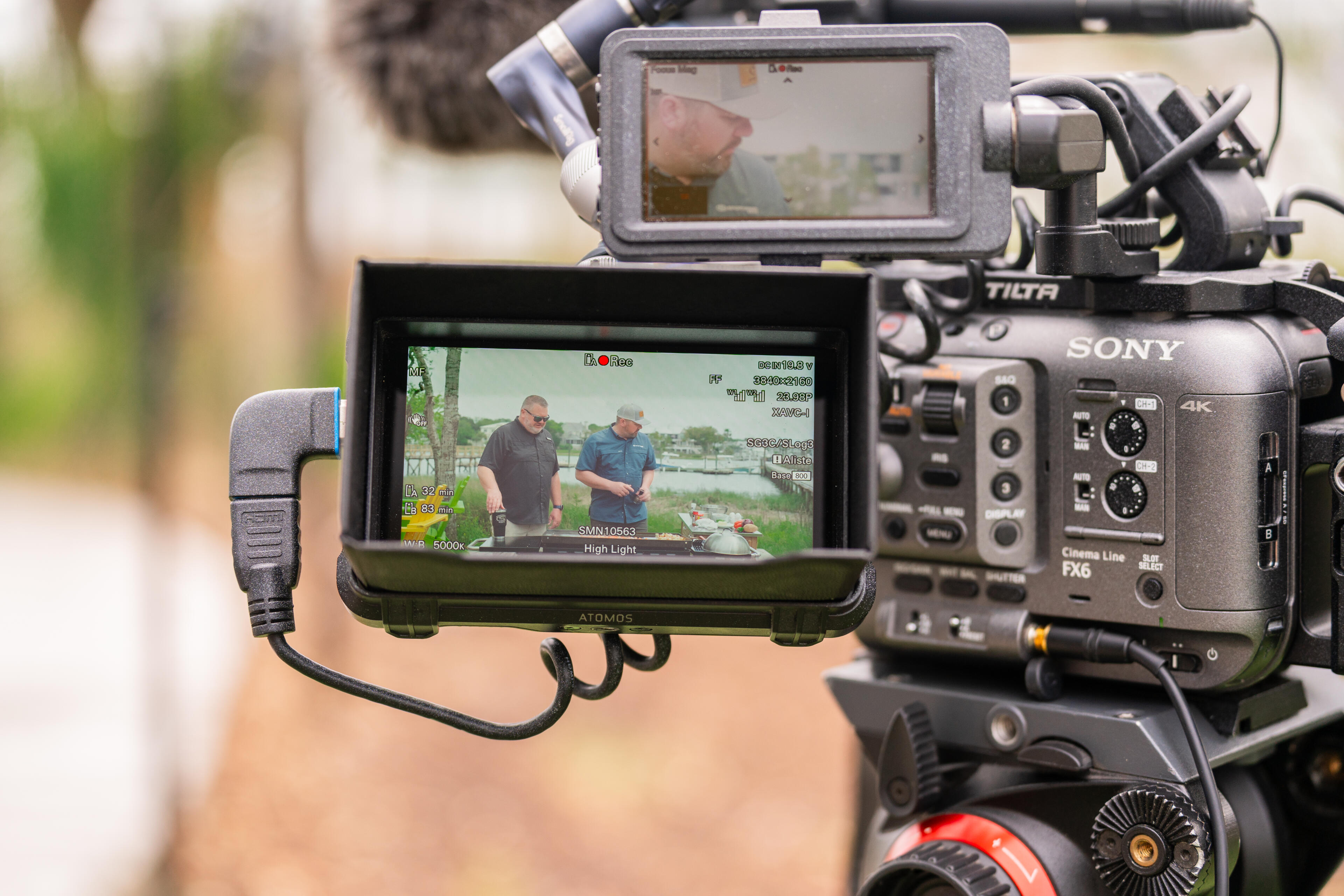 Professional video camera setup with external monitors showing two anglers fishing from a boat