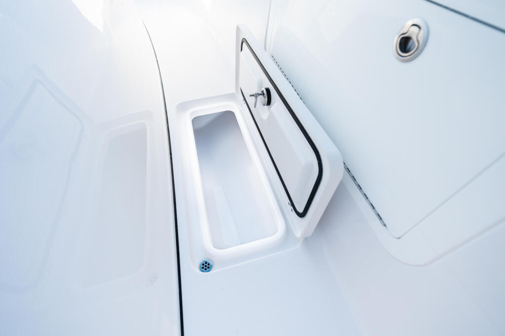 Overhead view of open hatch and livewell compartment on boat deck with drainage hole visible