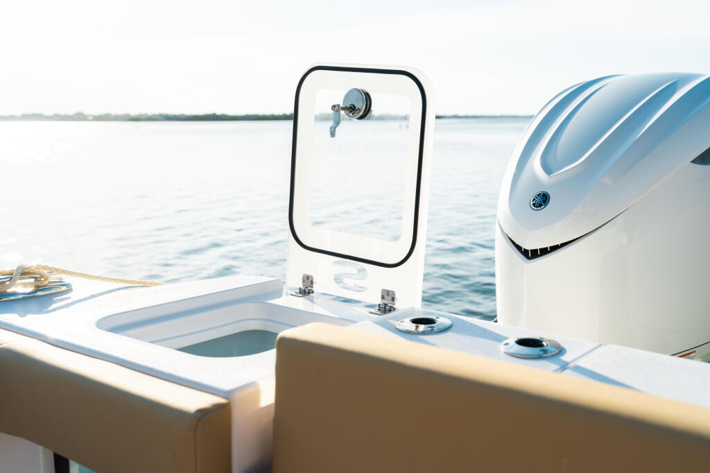 Console and helm station on boat with mirror, rod holders, and controls overlooking calm water