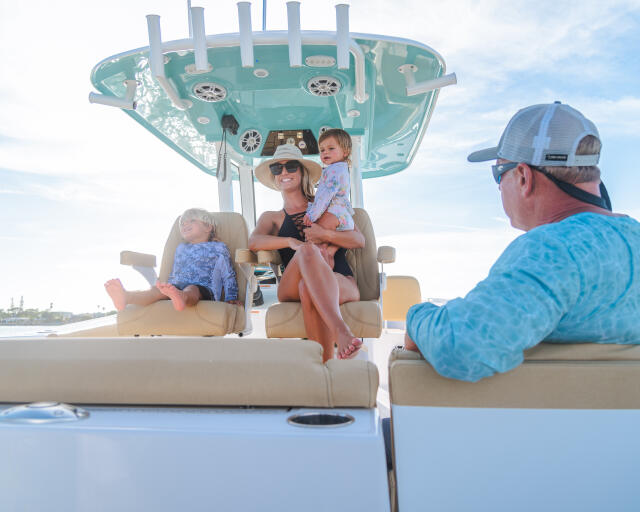 Family with two young children relaxing in shaded seating area on a center console boat