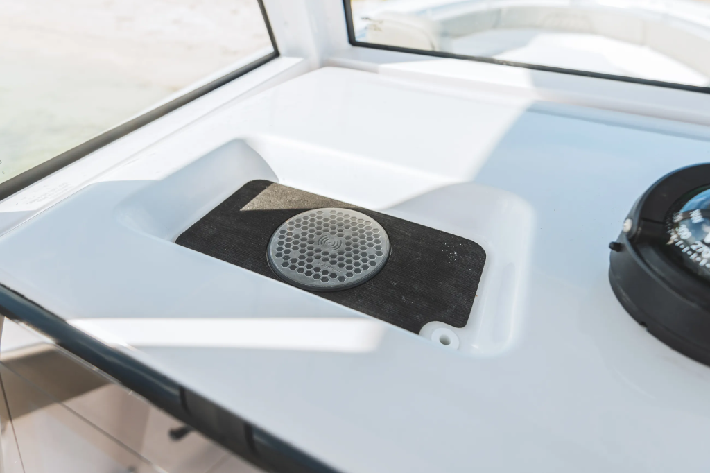 Wireless phone charger mounted on black pad in white console cup holder with compass visible nearby
