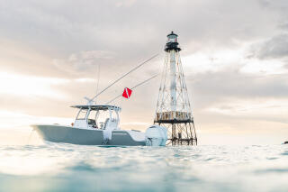 Center console fishing boat moored next to a navigational beacon in shallow offshore waters