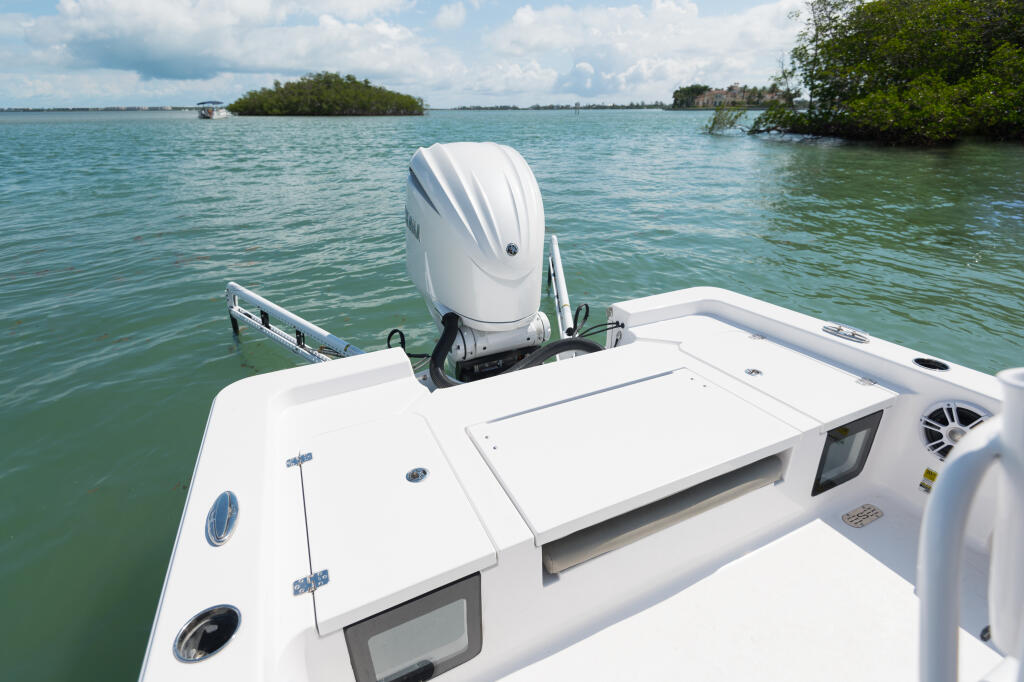 Rear deck view of a white bay boat with outboard engine in calm turquoise waters near mangrove islands