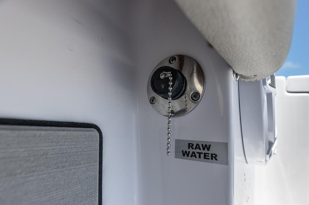 Raw water washdown valve with chain pull on white boat hull exterior