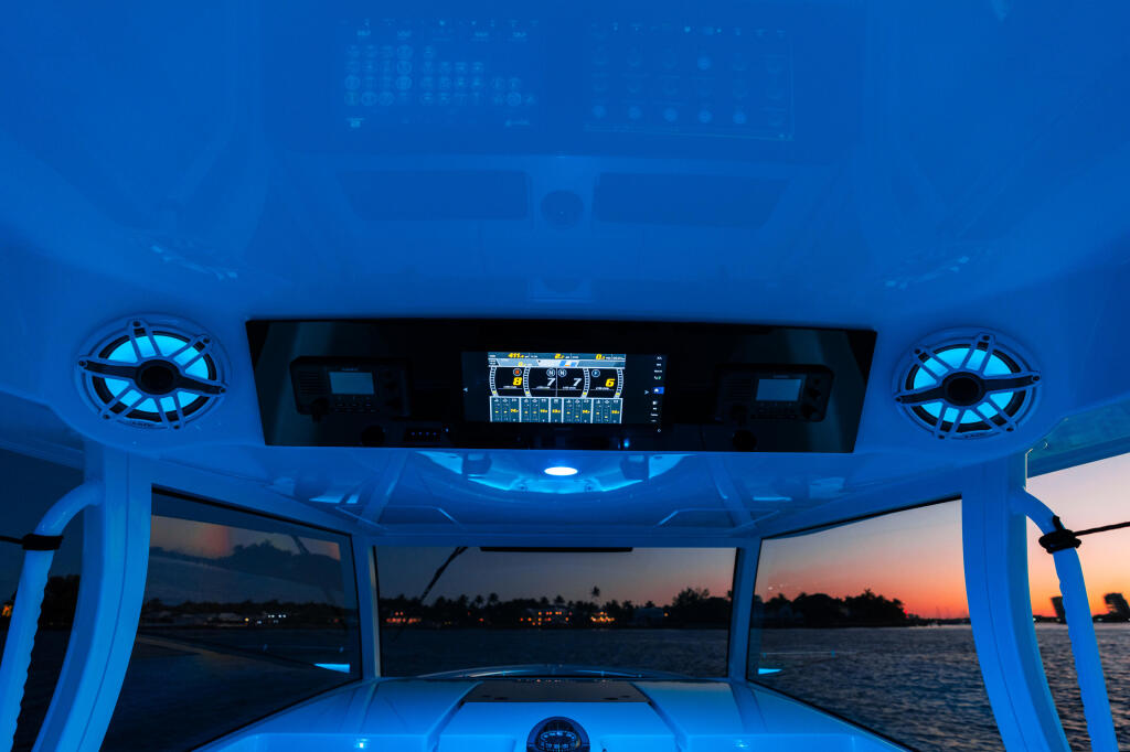 Boat helm at sunset with blue ambient lighting and Garmin GPS display visible overhead