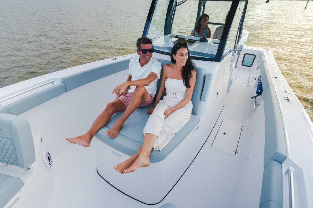 Couple relaxing on cushioned seating in the cabin of a white center console boat