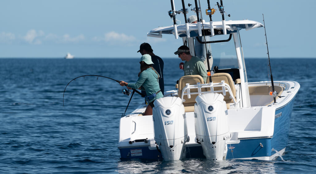 Angler with bent fishing rod on white center console boat in offshore waters