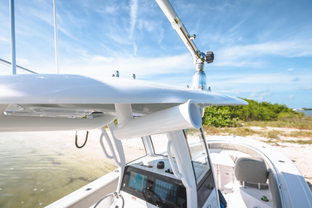Center console boat at shallow sandbar with electronics at helm and hard-top shade structure overhead