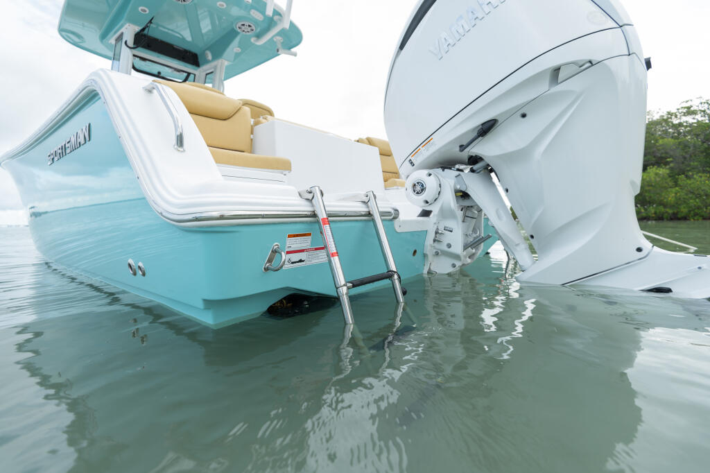 Turquoise and white center console boat with dual boarding ladders extended into shallow water