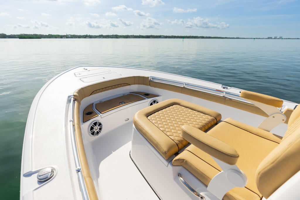 Spacious bow seating with tan quilted cushions and white fiberglass hull overlooking calm turquoise water