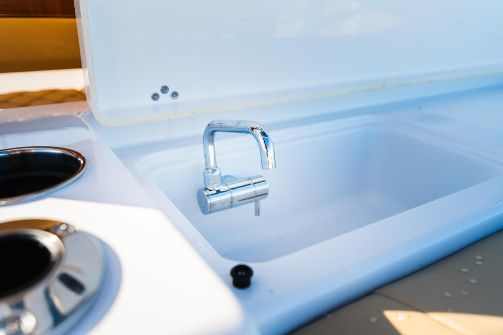 Chrome faucet above a white sink basin on boat with cup holders visible
