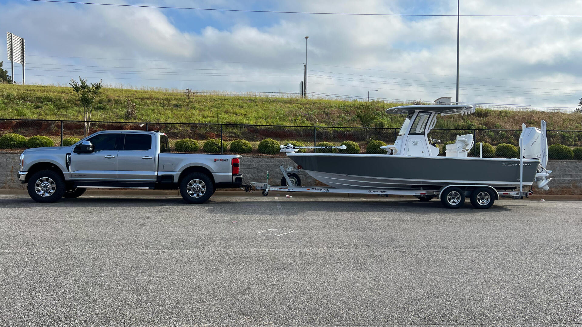 Silver Ford truck towing a white and gray fishing boat on a dual-axle trailer