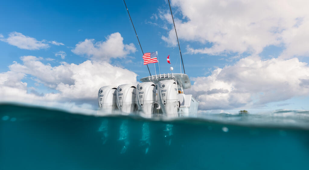 Center console boat with quad outboard engines captured in a split-level underwater and above-water shot