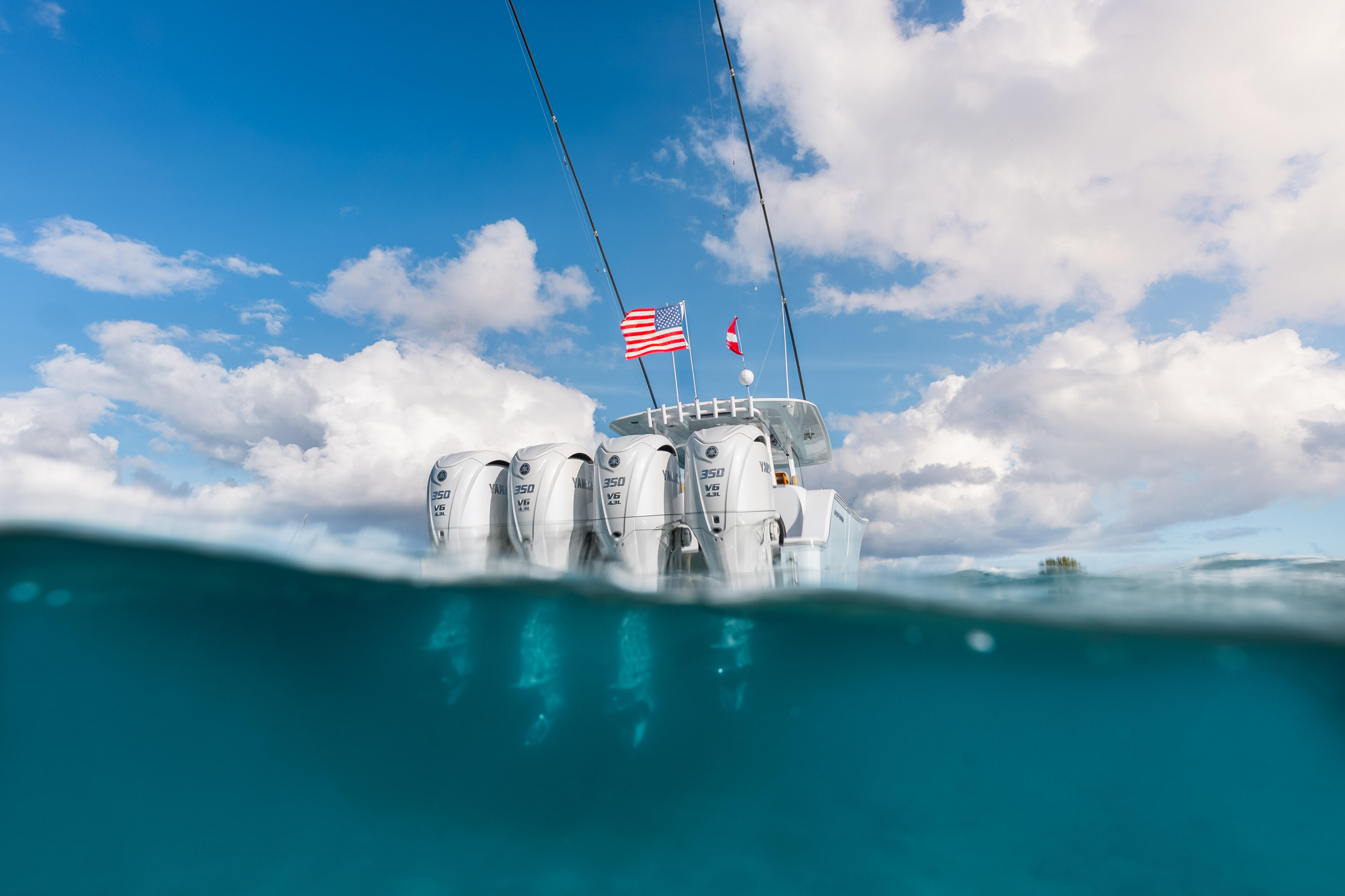 Center console boat with quad outboard engines captured in a split-level underwater and above-water shot