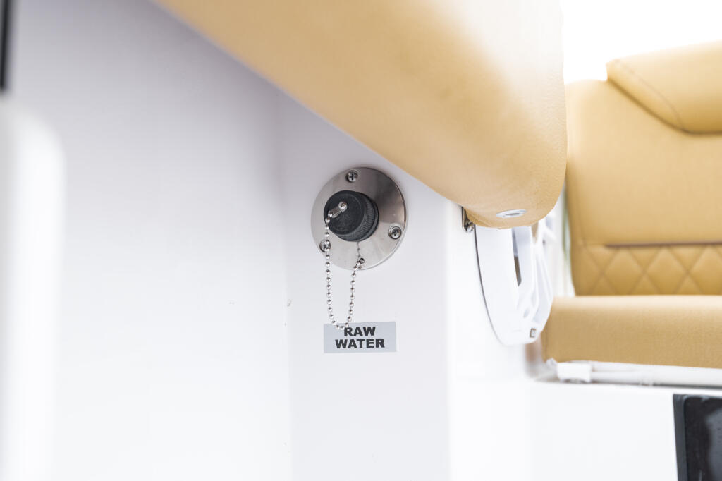 Raw water washdown valve mounted on white cabin wall with cream-colored seating visible above
