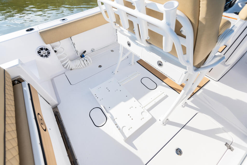 Center console boat deck with white railings, slide-out cooler tracks, and storage compartments overlooking green water