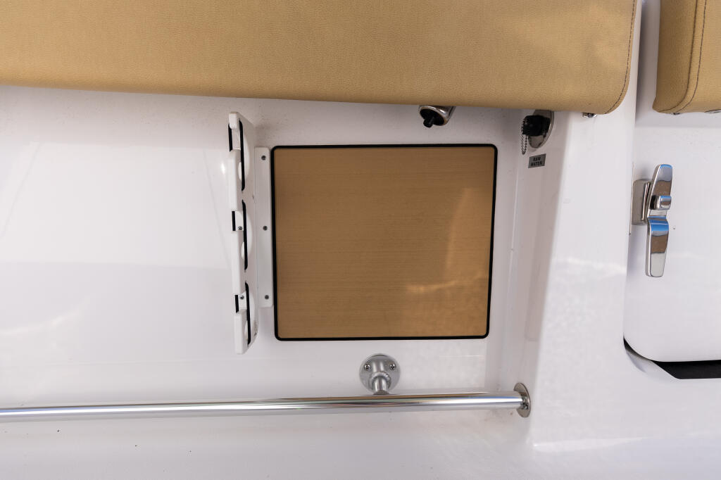 Overhead view of boat console interior showing tan upholstered backrest, window with shade, and chrome hardware details