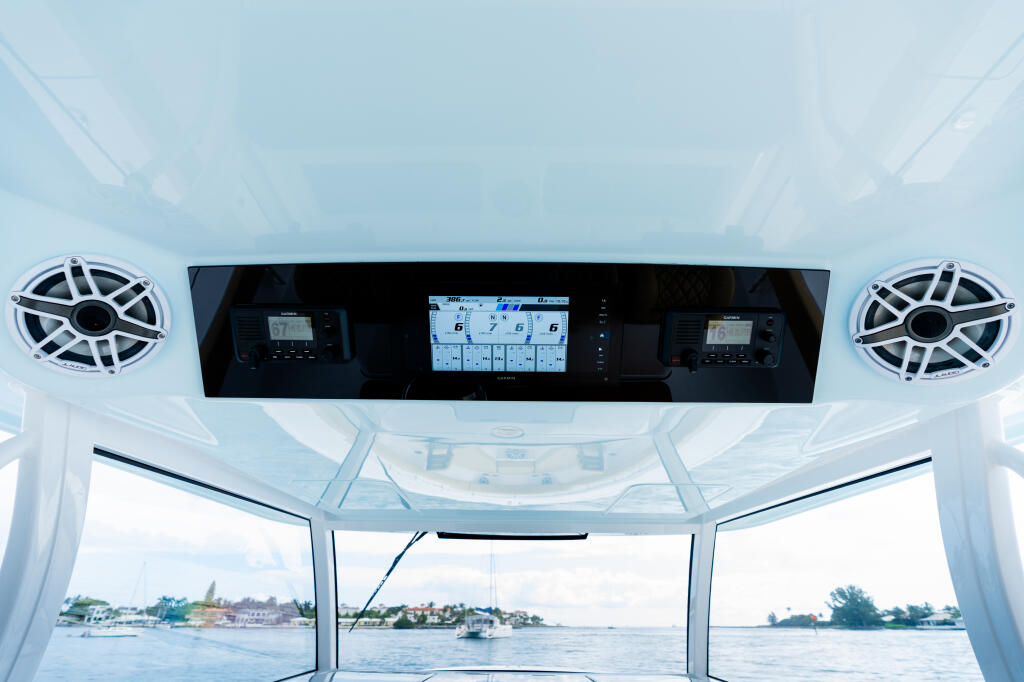 Boat helm interior with Garmin GPS touchscreen, dual speakers, and windshield view of waterfront marina