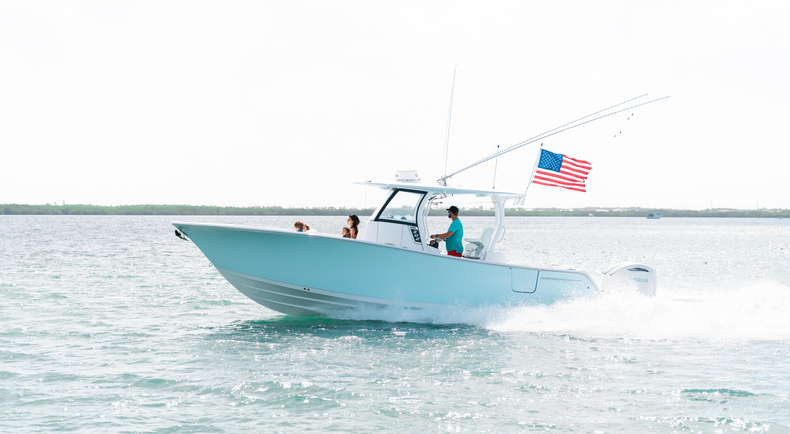 Turquoise center console boat running through shallow water with family aboard and American flag flying