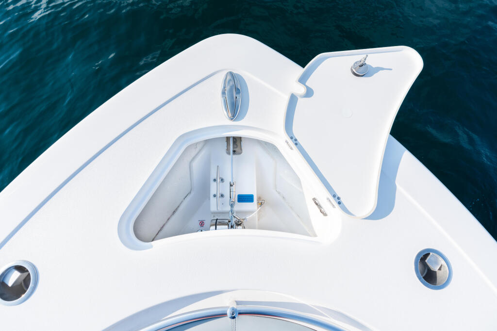 Overhead view of a white sport fishing boat's helm with windshield and control systems visible in clear turquoise water