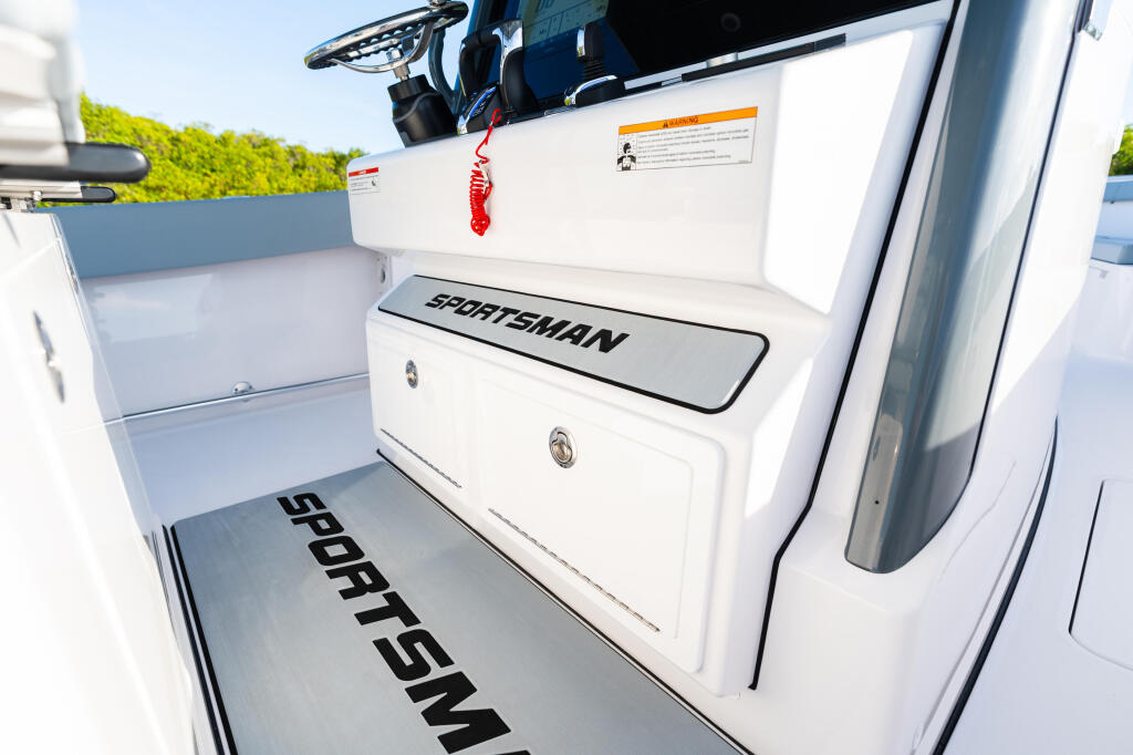 Sportsman boat cockpit with white seating, storage locker, and helm steering wheel in bright daylight