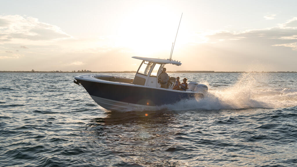 Center console boat running through shallow coastal waters at sunset with passengers aboard