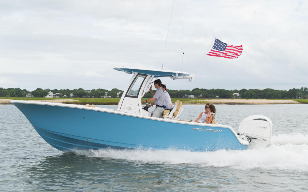 Blue and white center console boat running through shallow coastal waters with passengers and American flag flying
