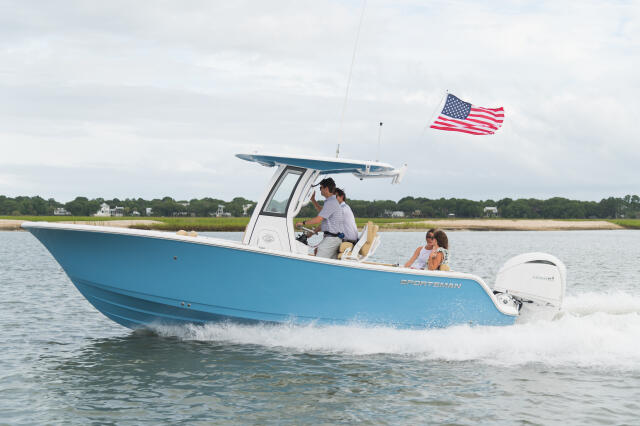 Blue and white center console boat running through shallow coastal waters with passengers and American flag flying