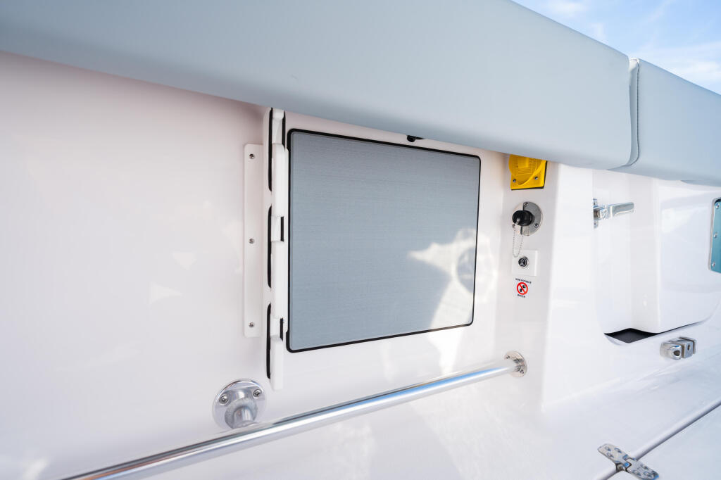Cabin window with tinted frame and safety controls on white boat hull exterior