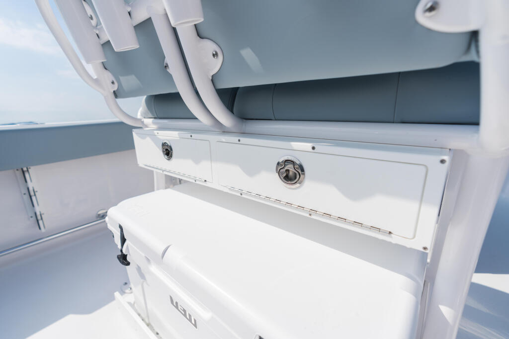Open livewell compartment with white cushioned seat and hardware on center console boat