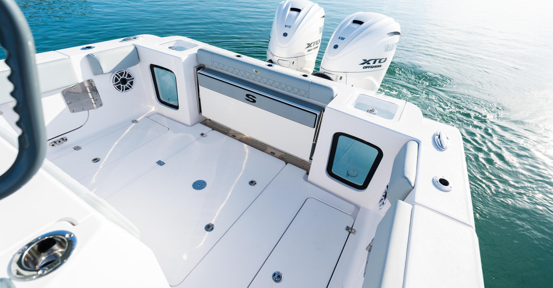 Open 322 center console boat with dual outboard engines and windshield viewed from above on calm turquoise water