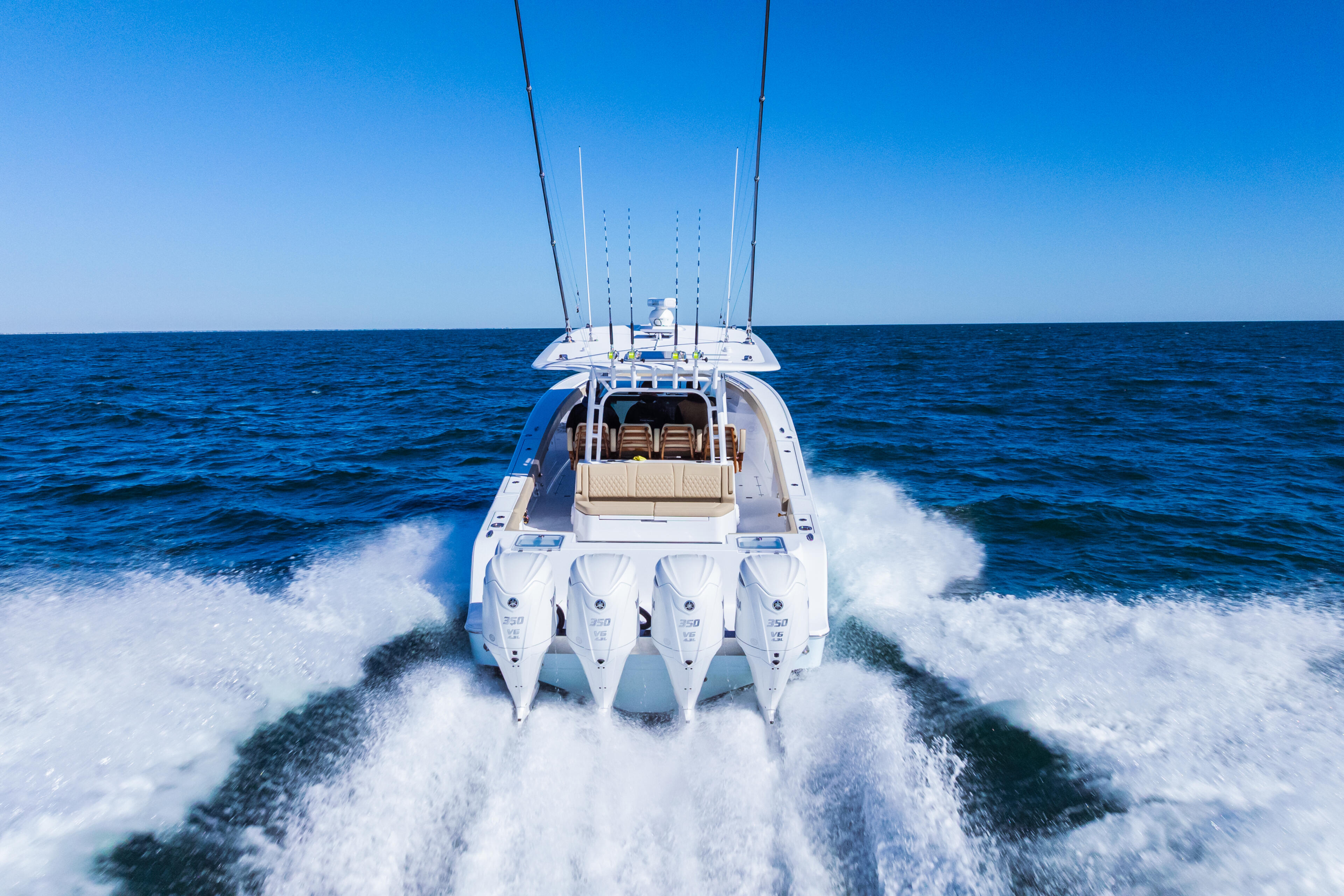 High-performance sport fishing boat running at speed through ocean waves with four outboard engines