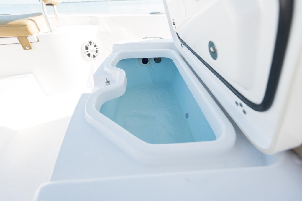 Overhead view of a boat's livewell with blue-tinted water and integrated seating nearby