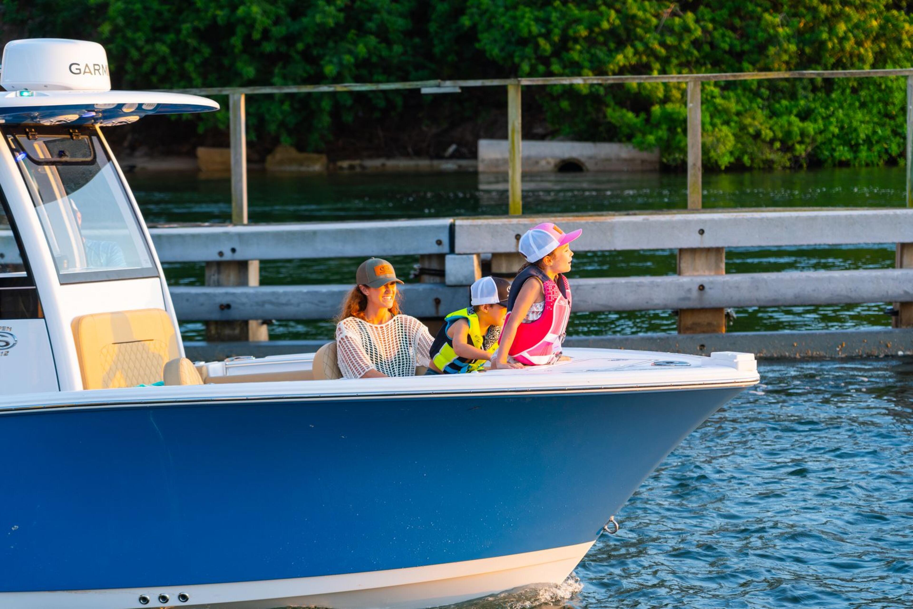 Family with young children in a blue and white boat docked at a wooden marina