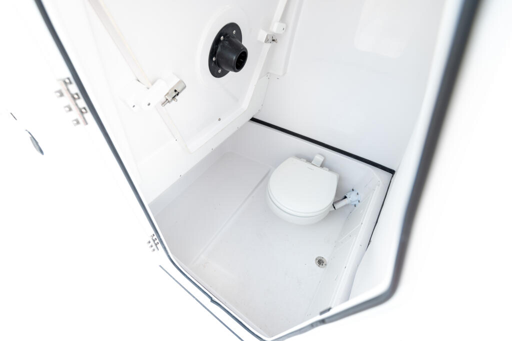 Compact boat cabin interior with white toilet, ventilation, and storage compartments
