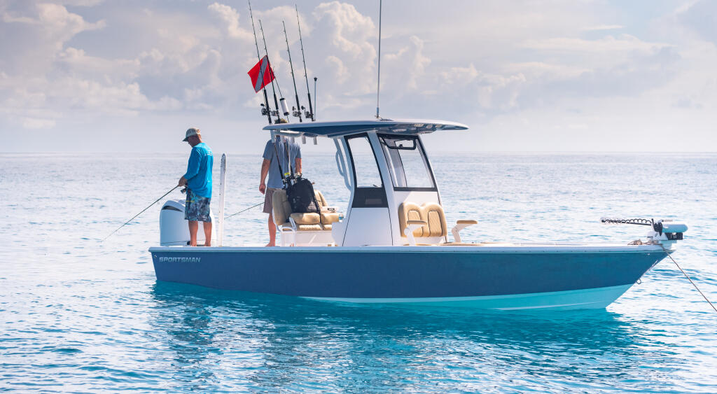 Anglers on a blue and white center console boat anchored in clear turquoise offshore waters
