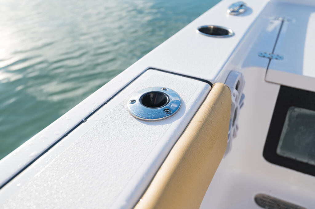 Flush-mount gunwale rod holders with stainless hardware on boat railing near open water