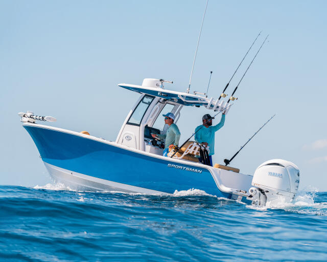 Two anglers fishing from a blue and white center console boat with multiple rods in the offshore waters