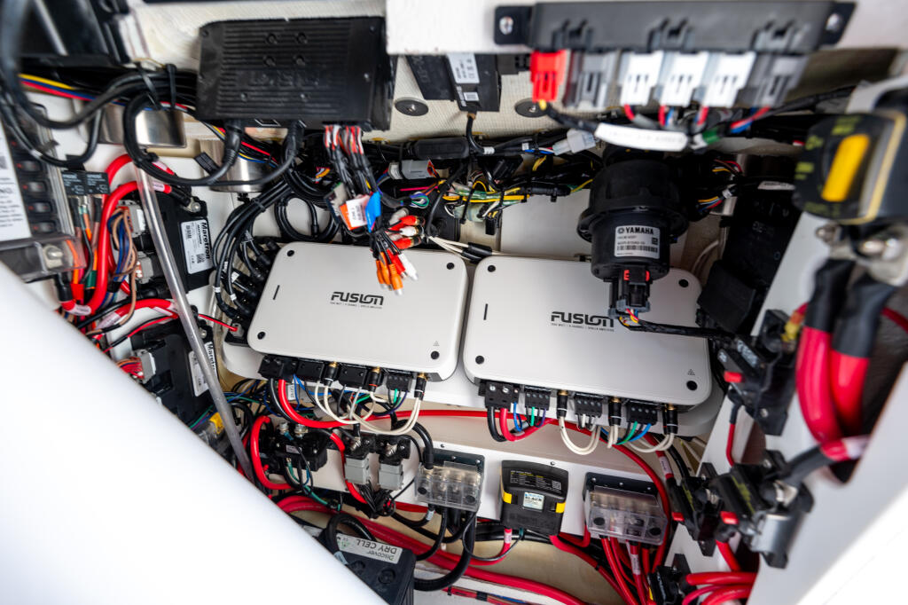 Close-up of boat electrical system with Fusion audio components, Yamaha engine control, wiring harnesses, and power distribution