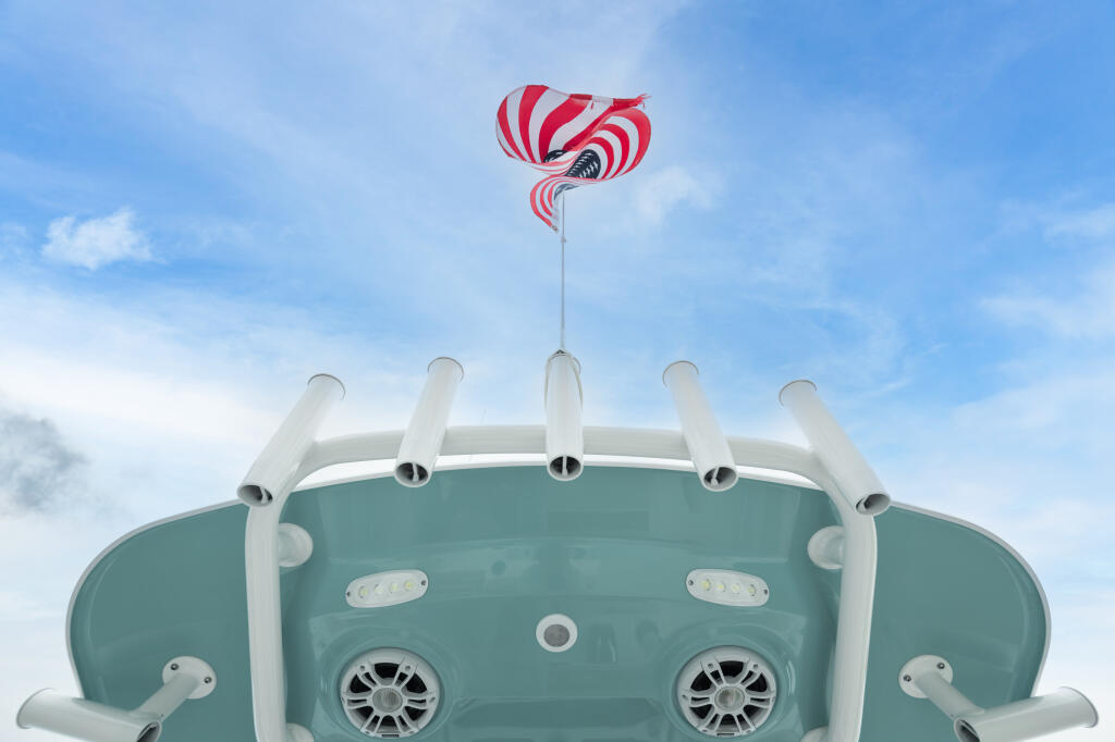 Red and white parachute deployed above the hardtop of a turquoise center console boat against blue sky