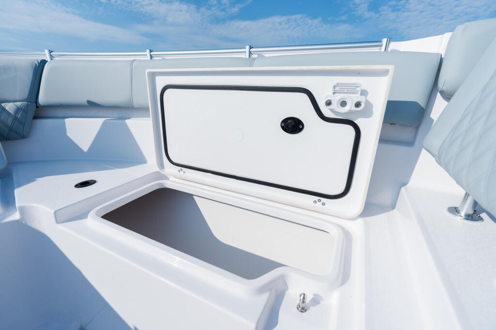 Starboard side storage locker and livewell on a white center console boat with blue sky above