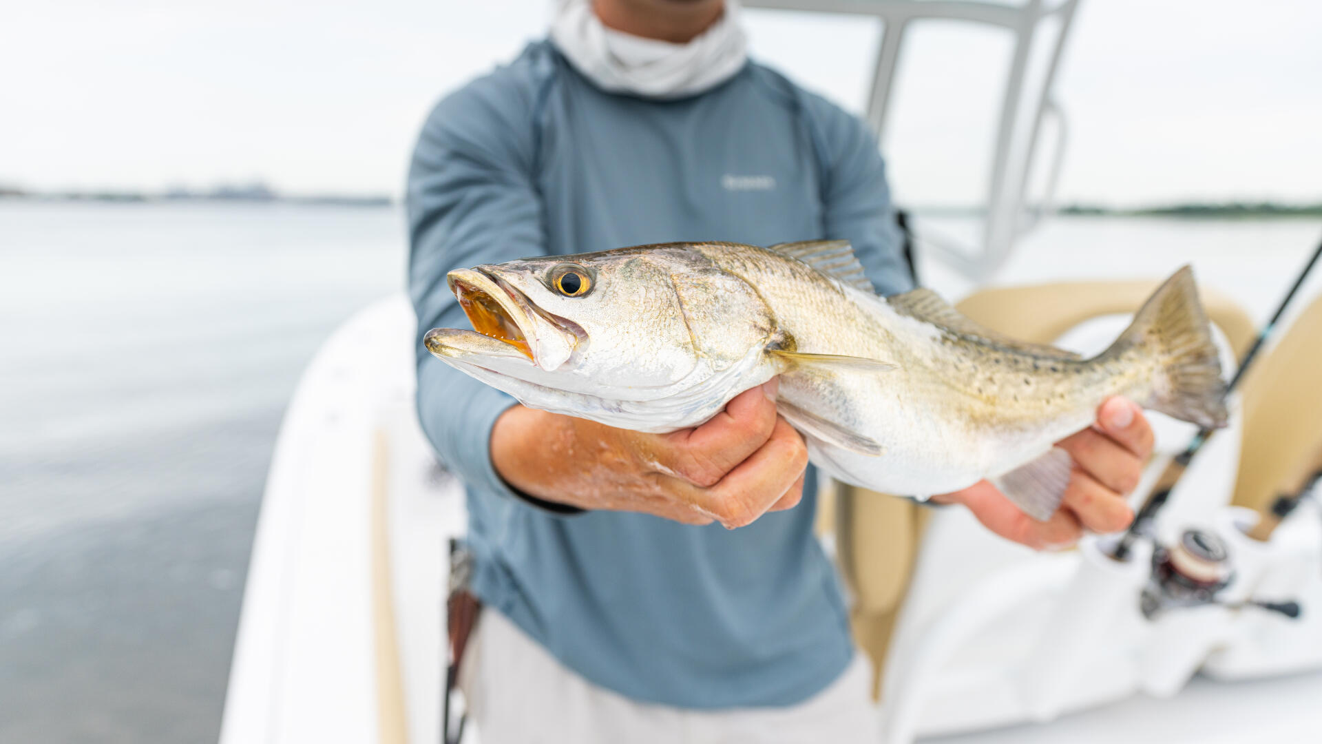 Angler holding a freshly caught speckled trout on a center console fishing boat