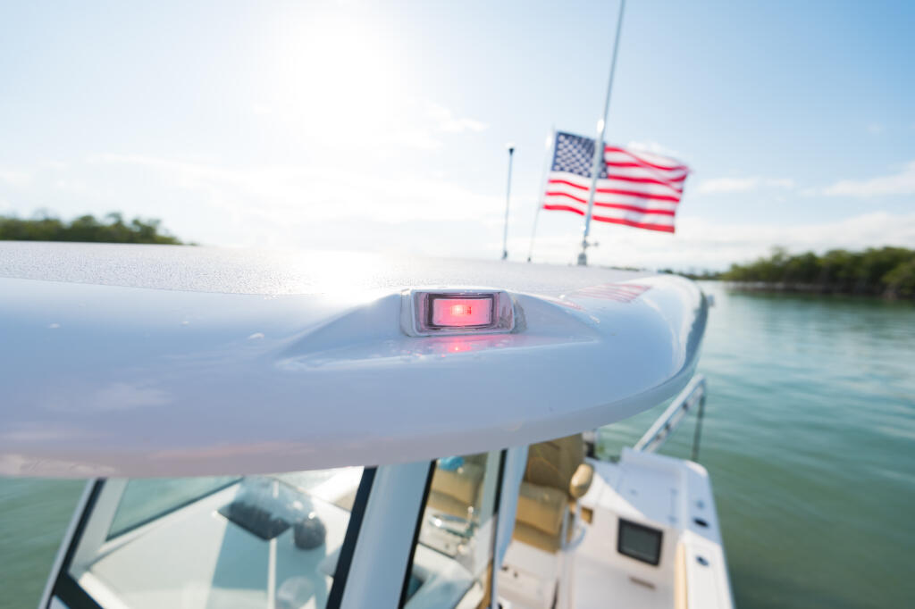 Close-up of molded-in navigation light on boat hard-top with American flag and water in background