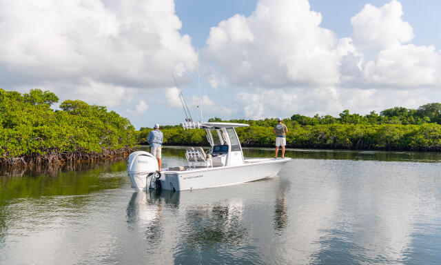 Fishing boat with anglers cruising through mangrove-lined shallow waters in Key Largo