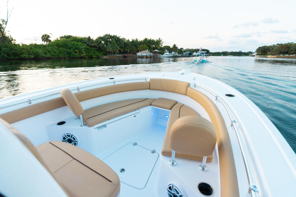 Bow seating area with tan cushioned seats overlooking a mangrove-lined waterway