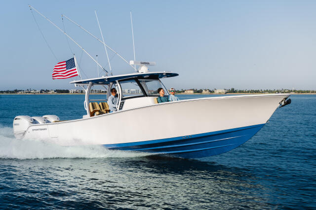 White and blue sportsman boat running through coastal waters with passengers and American flag flying