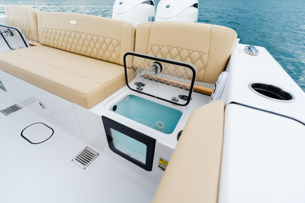 Cream-colored seating and open livewell with turquoise water visible on luxury fishing boat deck