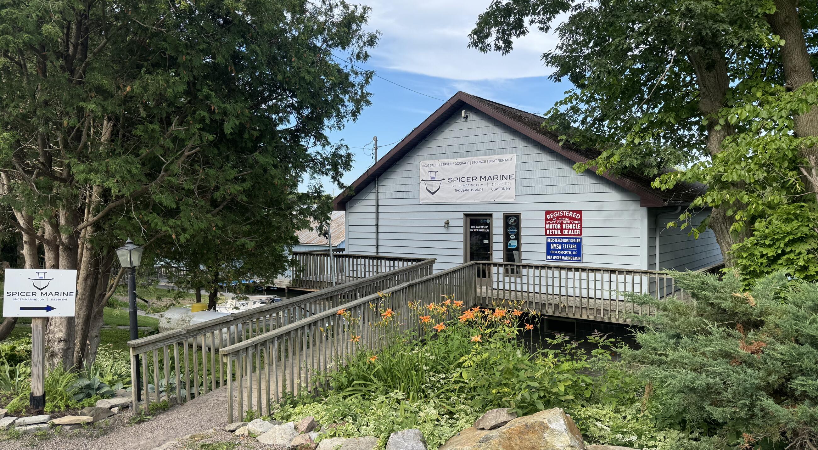 Spicer Marine storefront building with wooden deck and railing nestled among tall green trees